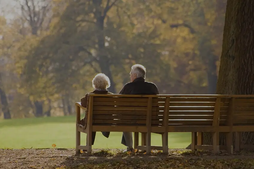 Loving Senior Couple Sitting Embraced on Park Bench
